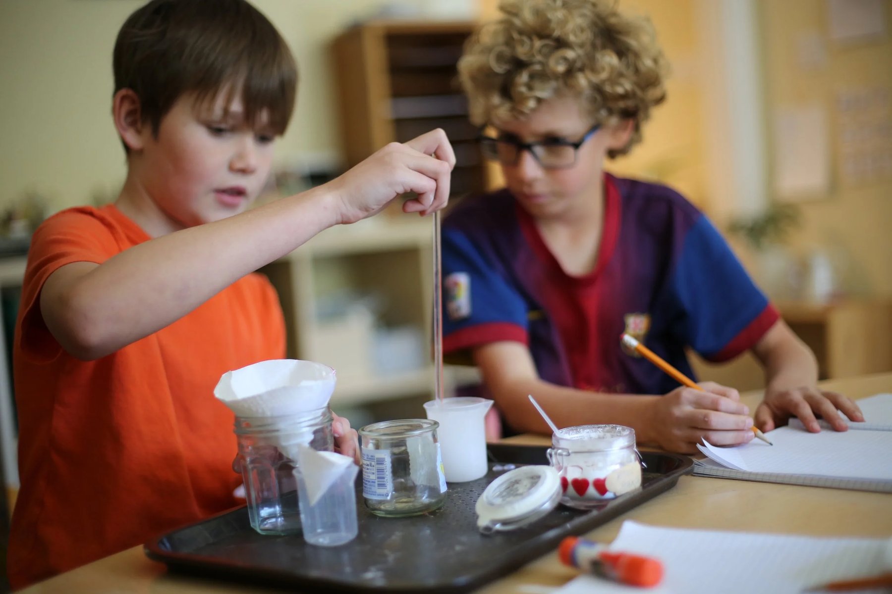 Two elementary students conducting a hands-on chemistry experiment with lab glassware