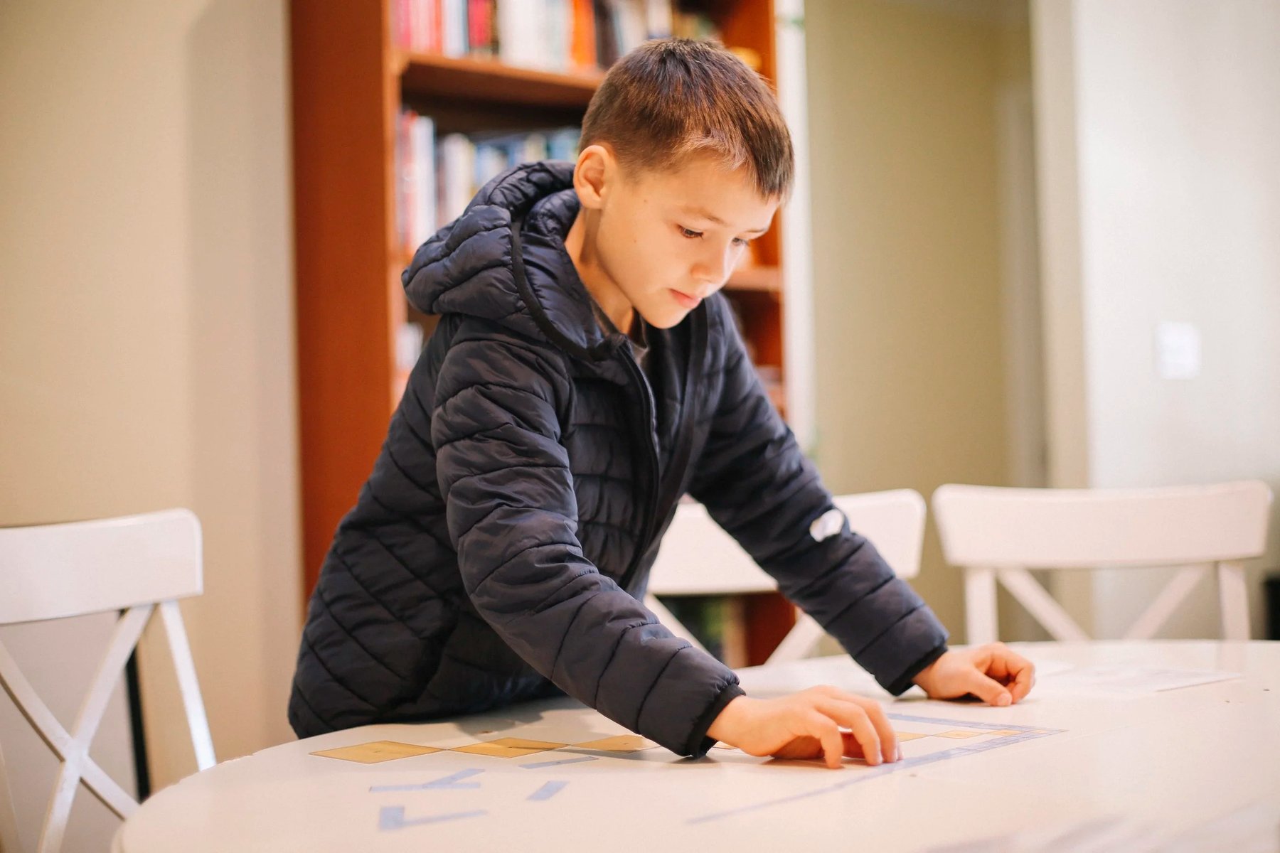 Student arranging bead bars and tiles on a Montessori decimal checkerboard